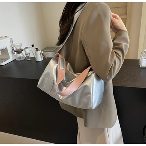 Detail view of metallic silver shoulder bag with contrasting pink strap and glossy texture