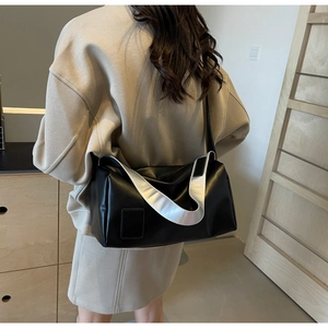 Detail of minimalist black soft leather shoulder bag with a stylish silver metal wide strap