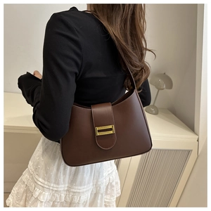 Detail of a dark brown crescent shoulder bag with a textured gold rectangular clasp