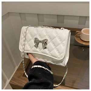Détail du sac bandoulière matelassé blanc avec nœud argenté et bandoulière chaîne