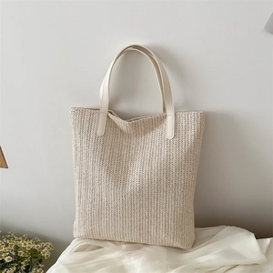 Minimalist beige woven tote bag with white leather straps and textured pattern