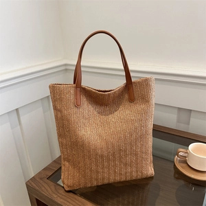 Brown woven tote bag with wavy patterns and leather handles in a minimal interior setting