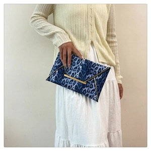 Close-up of blue and black leopard print envelope clutch with golden metallic edges