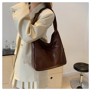 Brown matte leather shoulder bag with geometric stitching shown on a model