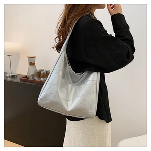 Silver geometric patchwork tote bag shown from side profile on a fashion model