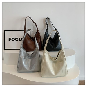 Multiple colors of geometric patchwork tote bags displayed on a white tiered platform