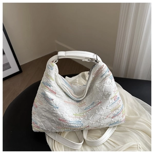 Close-up of white quilted tote bag with colorful embroidery and soft textured fabric