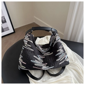 Detail of black tote bag showing colorful wave embroidery and textured quilted fabric