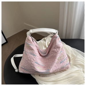 Pink textured fabric bag featuring colorful embroidery details and white top handles