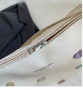Close-up of smooth silver metal zipper and colorful heart patches on beige tote bag