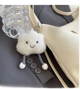Detail of a fluffy cloud plush keychain with a smile face on a beige leather handbag