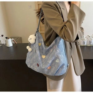 Detail of light blue denim heart tote bag with white cloud plush charm and large capacity