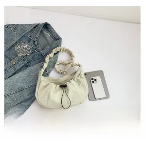 Detail view of beige pleated nylon shoulder bag showing interior capacity and size with iPad