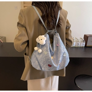 Blue denim tote bag with colorful heart patches and cloud charm on model's shoulder