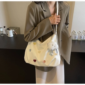 Detail of white tote bag with colorful heart patches and a soft cloud charm