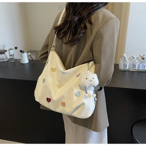 Detail of cream tote bag with colorful heart patches and cloud plush pendant