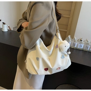 Close-up of a white leather tote bag with colorful heart patches and a cloud charm