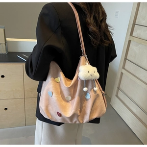 Detail of pink tote bag with heart appliques and cloud charm on a shoulder strap