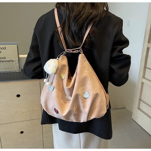Detailed view of pink heart-decorated tote bag with plush ball charm on a model