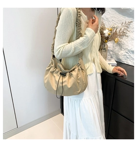 Detail of beige pleated crossbody bag with cloud-shaped shoulder strap and black drawstring