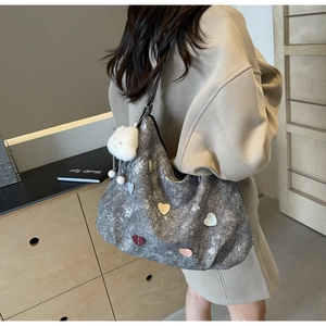 Detail of grey heart tote bag with multi-colored patches and white fuzzy keychain