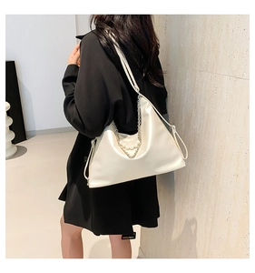 Detail of minimalist cream shoulder bag featuring elegant pearl and metal chain accents