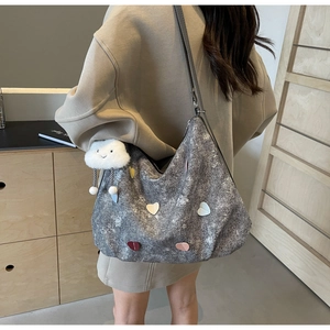 Detail of grey canvas tote bag with heart patches and white cloud plush charm