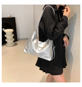 Detail of silver metallic hobo bag with pearl chain decoration on black outfit