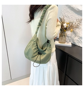 Close-up of green crossbody bag featuring ruched strap and adjustable drawstring detail