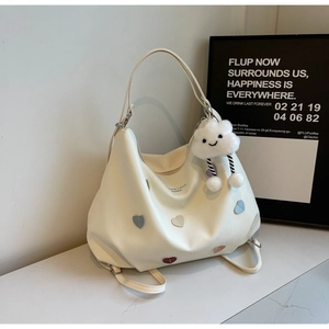 Detail of cream white tote bag with colorful heart patches and cloud plush pendant