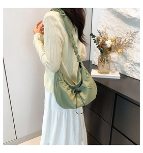 Detail of light green pleated tote bag featuring drawstring closure and soft fabric texture
