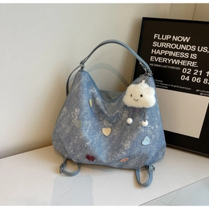 Close-up of blue denim tote bag with colorful heart patches and cloud charm