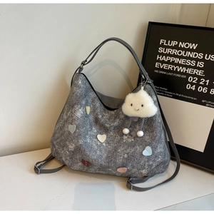 Detail of silver tote bag with colorful heart patches and plush cloud charm accessory