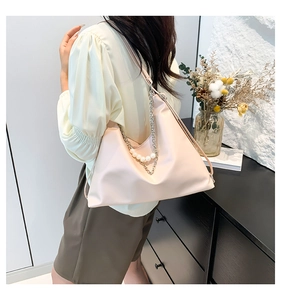 Model wearing a soft pink shoulder bag with elegant metal chain and white pearl details