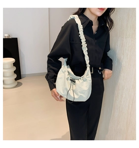 Detail of light beige pleated tote bag with drawstring closure and wide ruched shoulder strap