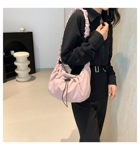 Detail of light pink pleated shoulder bag with drawstring closure worn by model