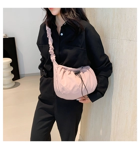 Detail of pink pleated crescent bag showing nylon texture and drawstring buckle on model