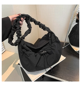 Detail of black pleated nylon tote bag featuring ruched strap and drawstring closure