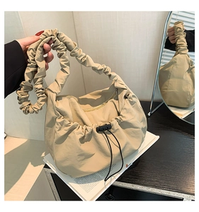 Detail of beige pleated tote bag with cloud-style handle and drawstring closure