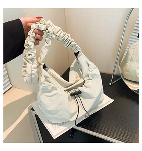 Detail of off-white pleated tote bag showing fabric texture and drawstring accent