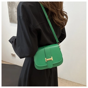 Detailed view of the green leather saddle bag featuring a gold metal H buckle and strap