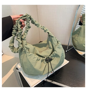 Detail of sage green pleated tote bag with drawstring buckle and cloud-style shoulder strap