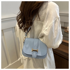 Close-up of light blue crossbody bag featuring a golden H-buckle and elegant PU texture