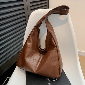 Brown vintage hobo shoulder bag with geometric patchwork design on white chair