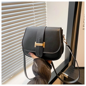 Close-up of black leather saddle bag featuring a prominent gold H-shaped metal buckle