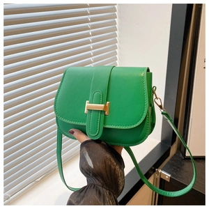 Close-up of bright green saddle bag featuring a gold H-buckle and sleek leather texture
