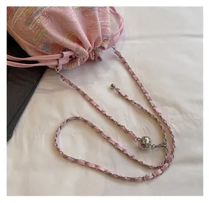 Dettaglio della borsa a secchiello rosa ricamata con tracolla a catena e sfera d'argento