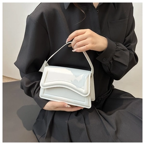 Close-up of white glossy patent leather handbag with wavy stitching and slim handle