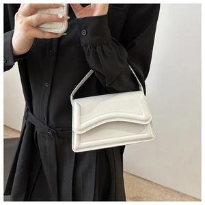 Detail of white mini square bag showing double wavy pleated flap and polished texture