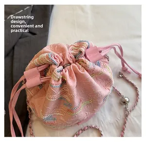 Dettaglio della borsa a secchiello rosa con coulisse, ricamo a onde e catena in metallo